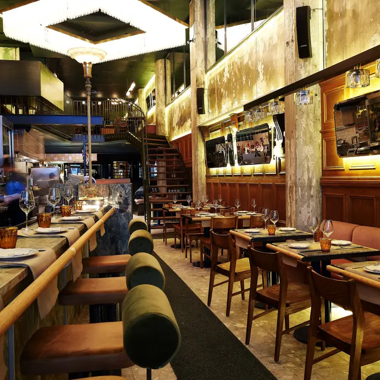 A dining room with copper-toned walls lined with mirrors and mahogany-colored furniture at Ibérica in Montreal