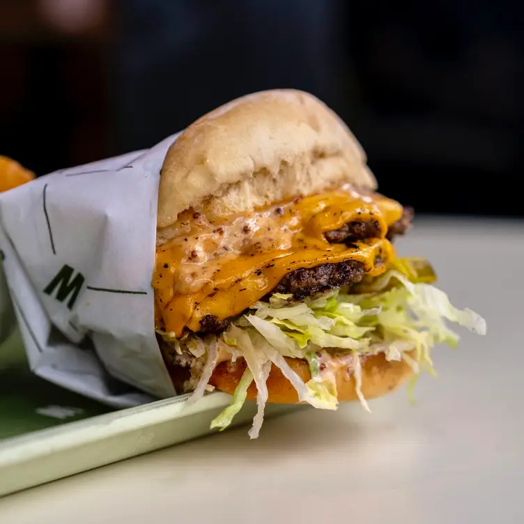 A burger wrapped in paper filled with salad, meat and melted cheddar at Bells & Whistles, one of the best burger joint in Vancouver