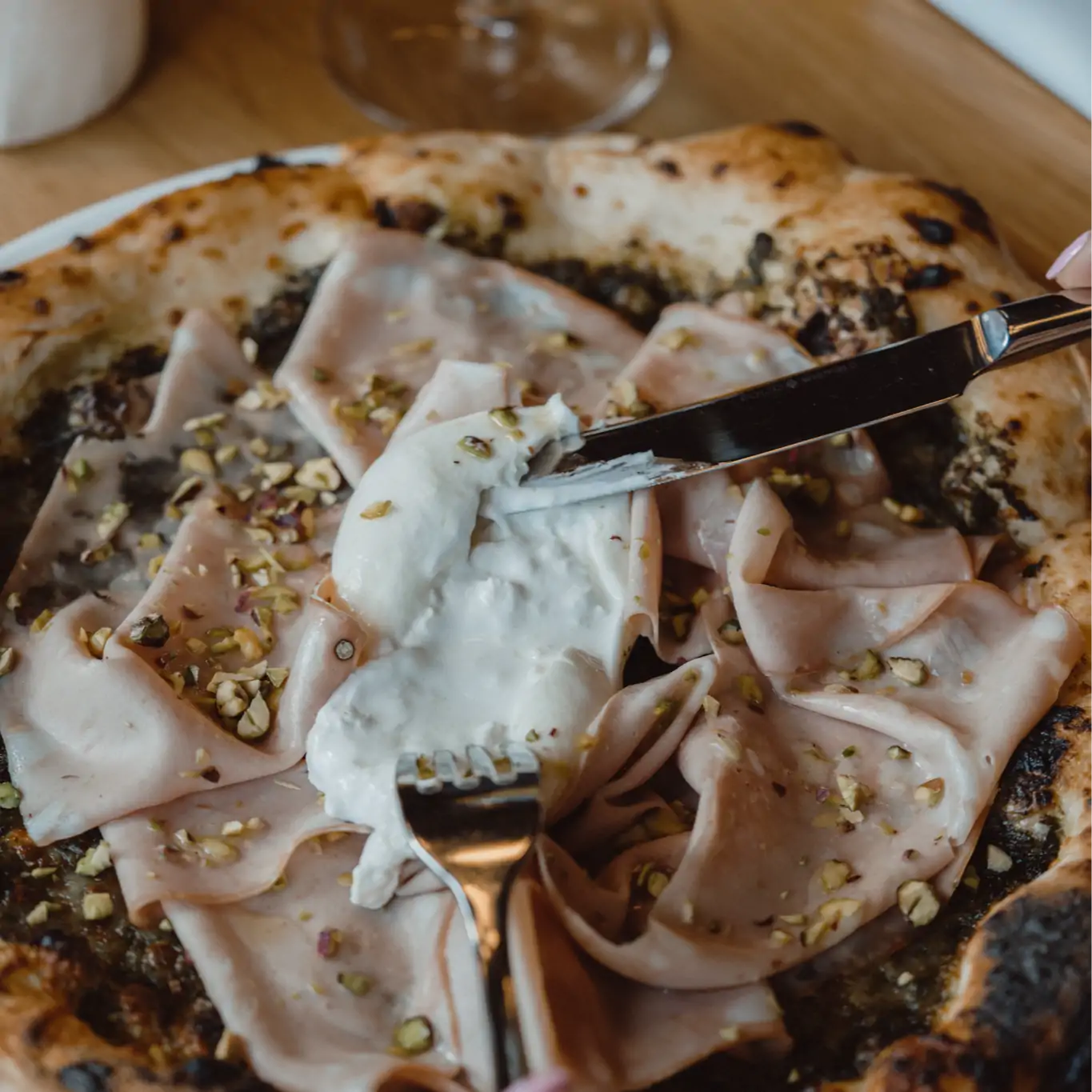 A diner cuts a bufala on top of a mortadella pizza at Ristorante Donato in Montreal