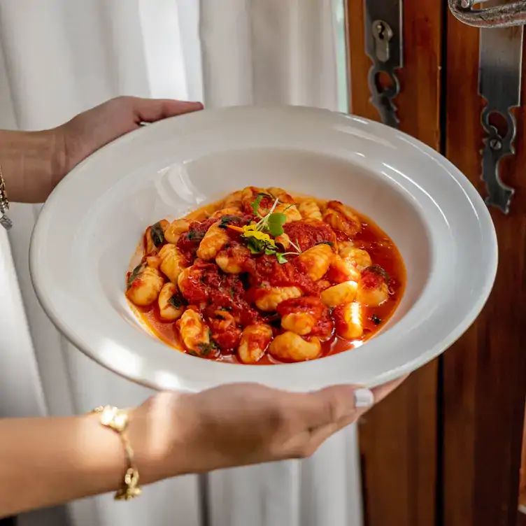 A waitress holds a bowl of tomato gnocchi at Le Muscadin, one of the best Italian restaurants in Old Montreal