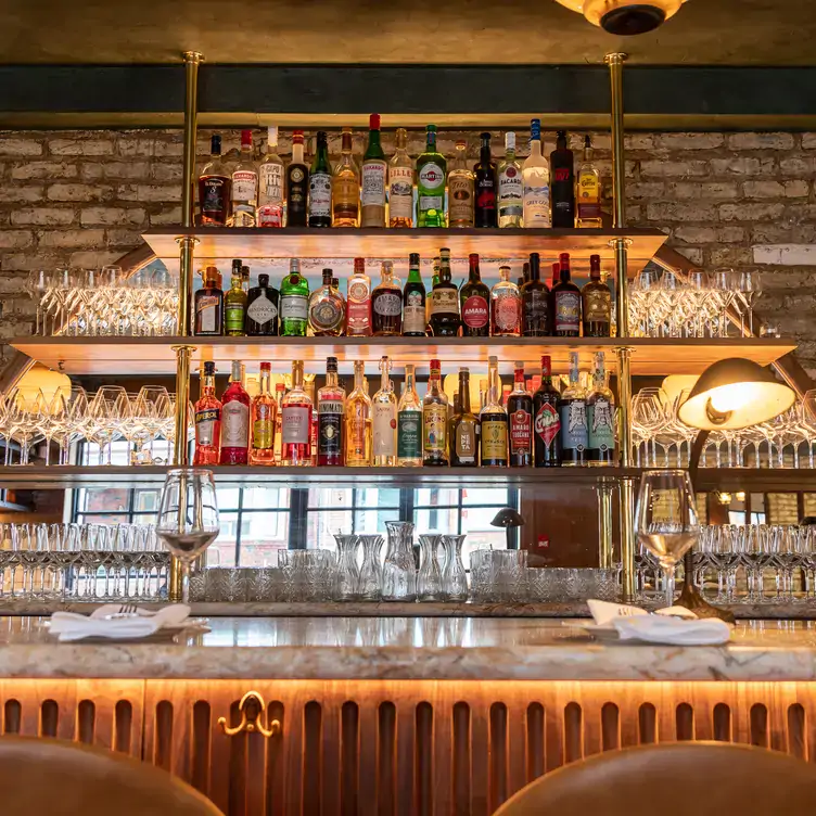 A bar with exposed brick walls and bottles lined up on shelves at Enoteca Sociale