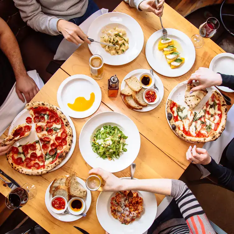 A spread of Italian dishes featuring pizza and pasta at Pizzeria Libretto, one of the best pizza restaurants in Toronto