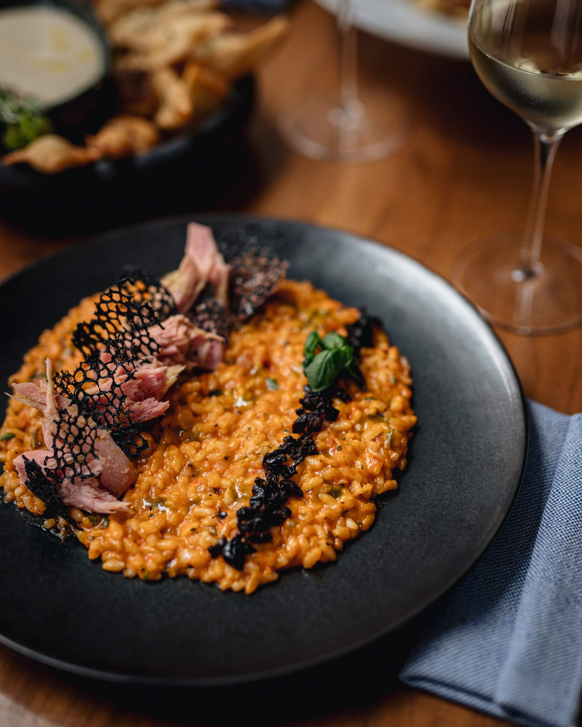 Risotto avec huile de basilic et thon rouge poché dans une assiette noire dans un restaurant