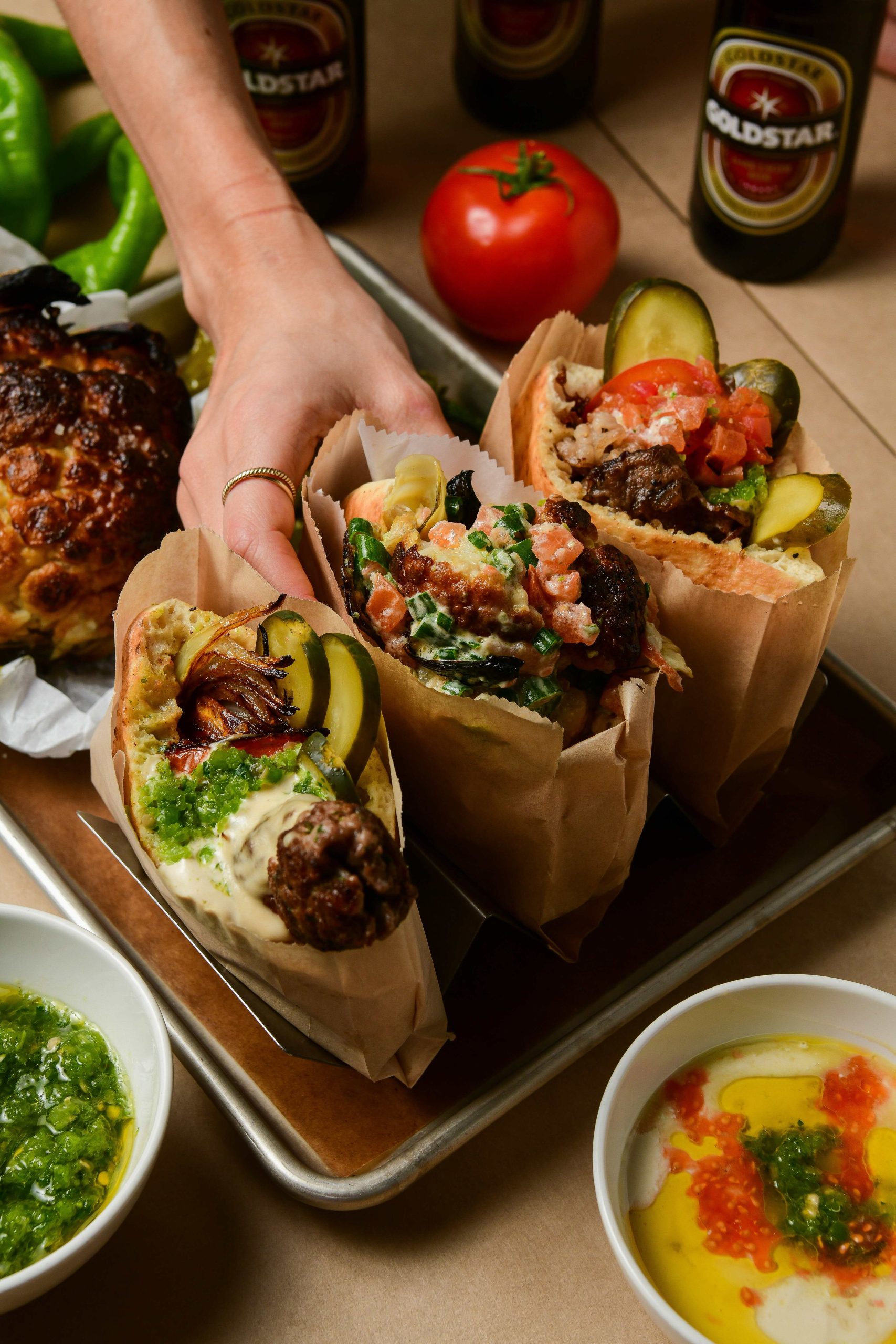 Three pitas wrapped in brown paper and filled with vegetables and meat at a restaurant.