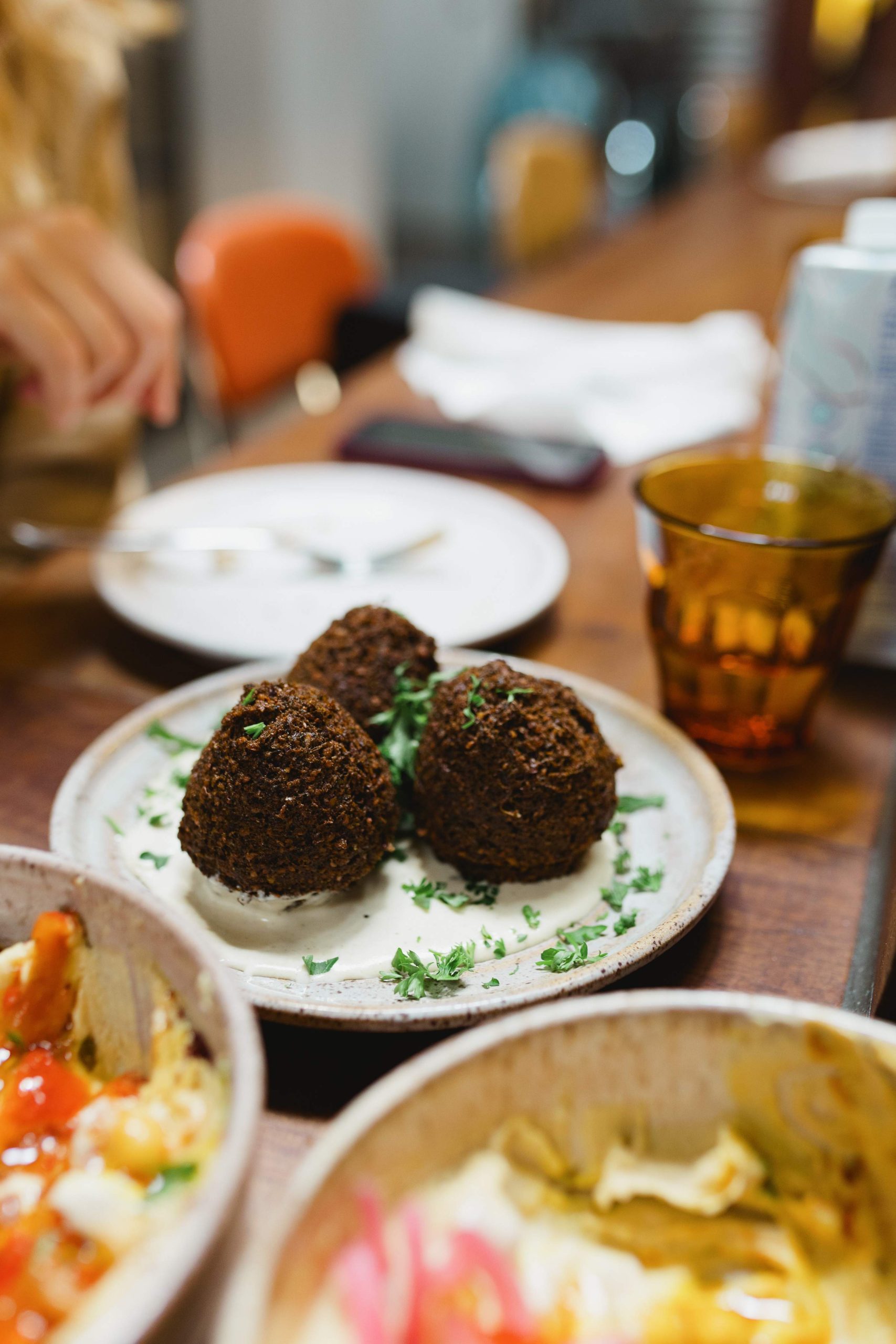 A white plate contains three brown falafels topped with herbs at Parallel, a restaurant in Toronto