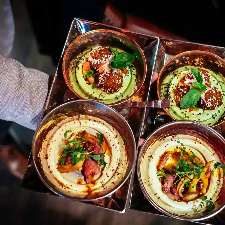 A waiter carries a tray of Syrian-inspired dishes at Damas, one of the best terrace restaurants in Montreal