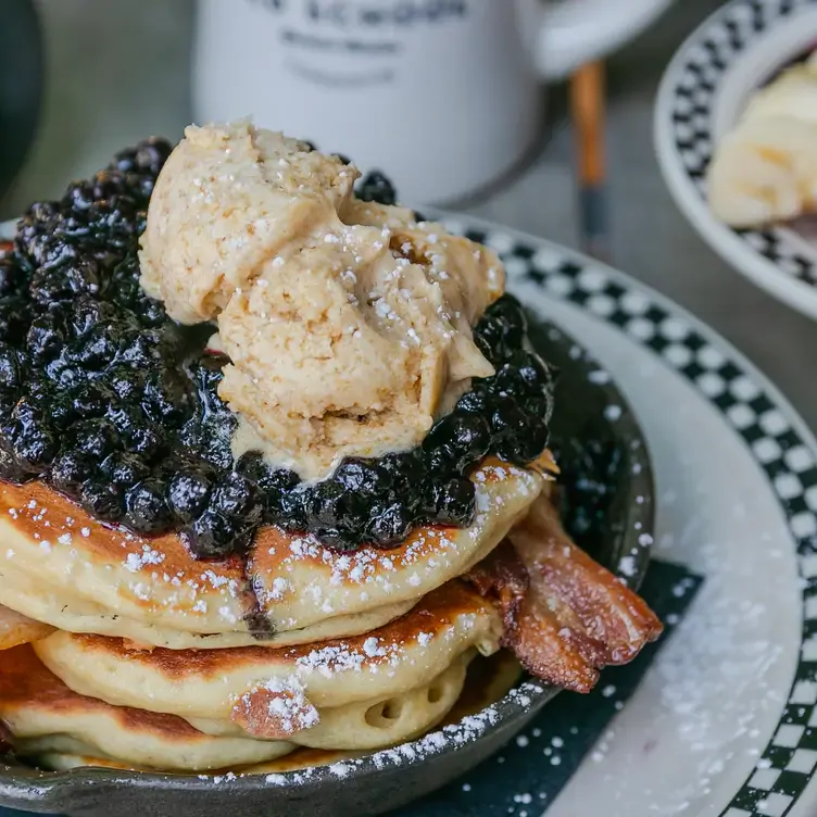 A stack of pancakes topped with blueberries, bacon, ice cream and maple syrup at Old School - Toronto