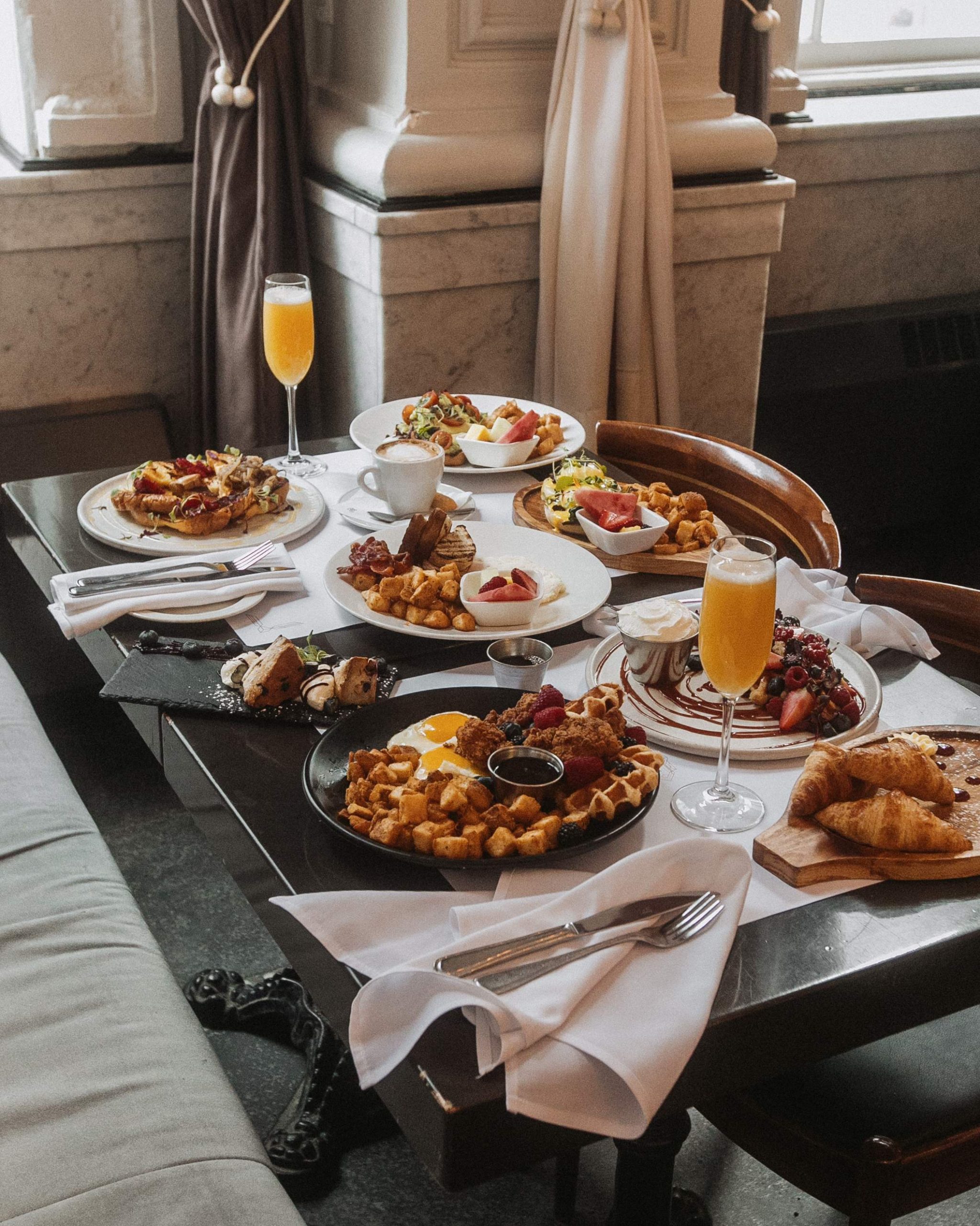 Un petit-déjeuner composé d'œufs, de pommes de terre, de pâtisseries et de mimosas chez Brasserie 701