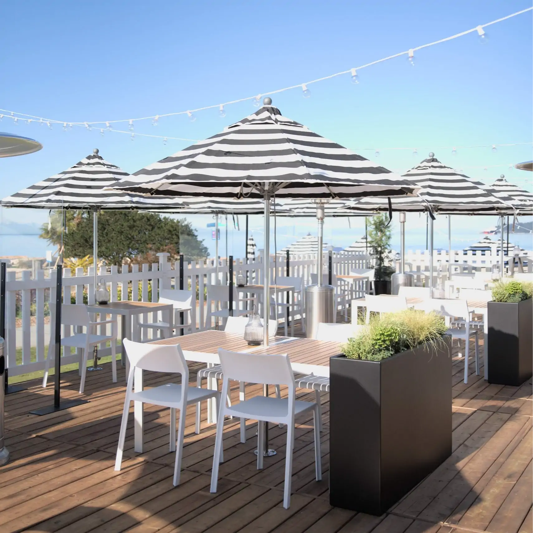 An ocean front patio with string lights and umbrellas at Beach House in Vancouver