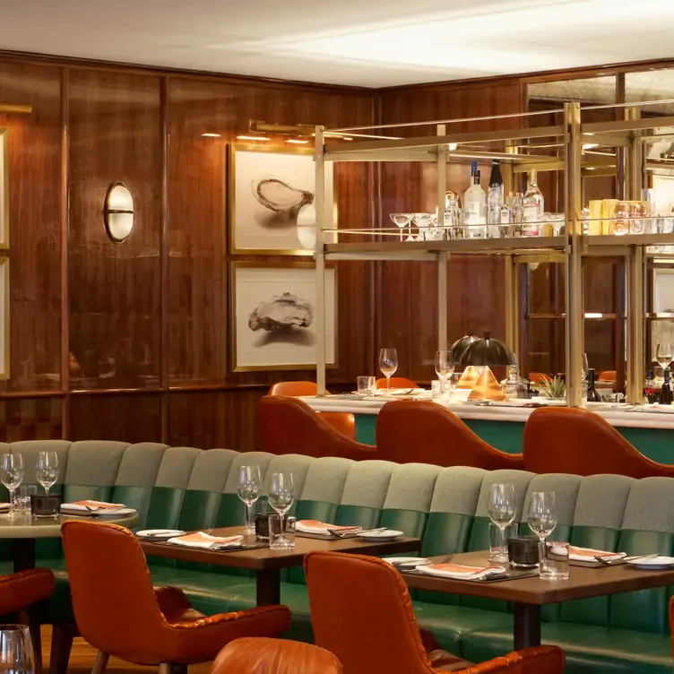 Elegant wood-panelled interiors with green banquettes and a bar at Café Boulud