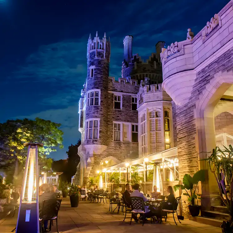 Outdoor dining set up complete with heaters and string light at the foot of a historical castle at BlueBlood Steakhouse, one of the best patios in Toronto