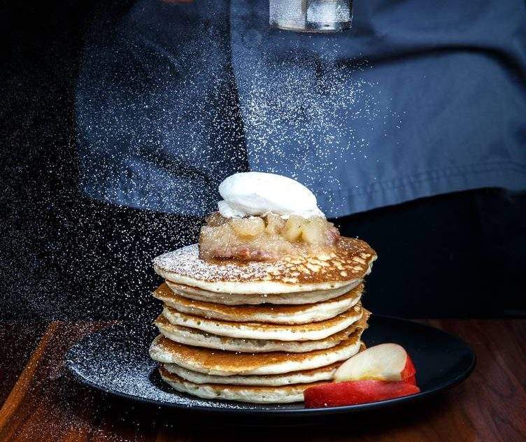 A plate of pancakes topped with powdered sugar and apples at Notch8.