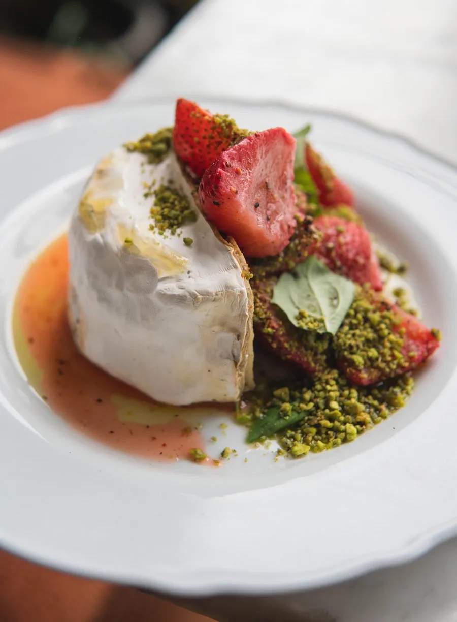 Plant-based brie cheese topped with slices of strawberries and crumbled nuts at Toronto Italian restaurant Gia.