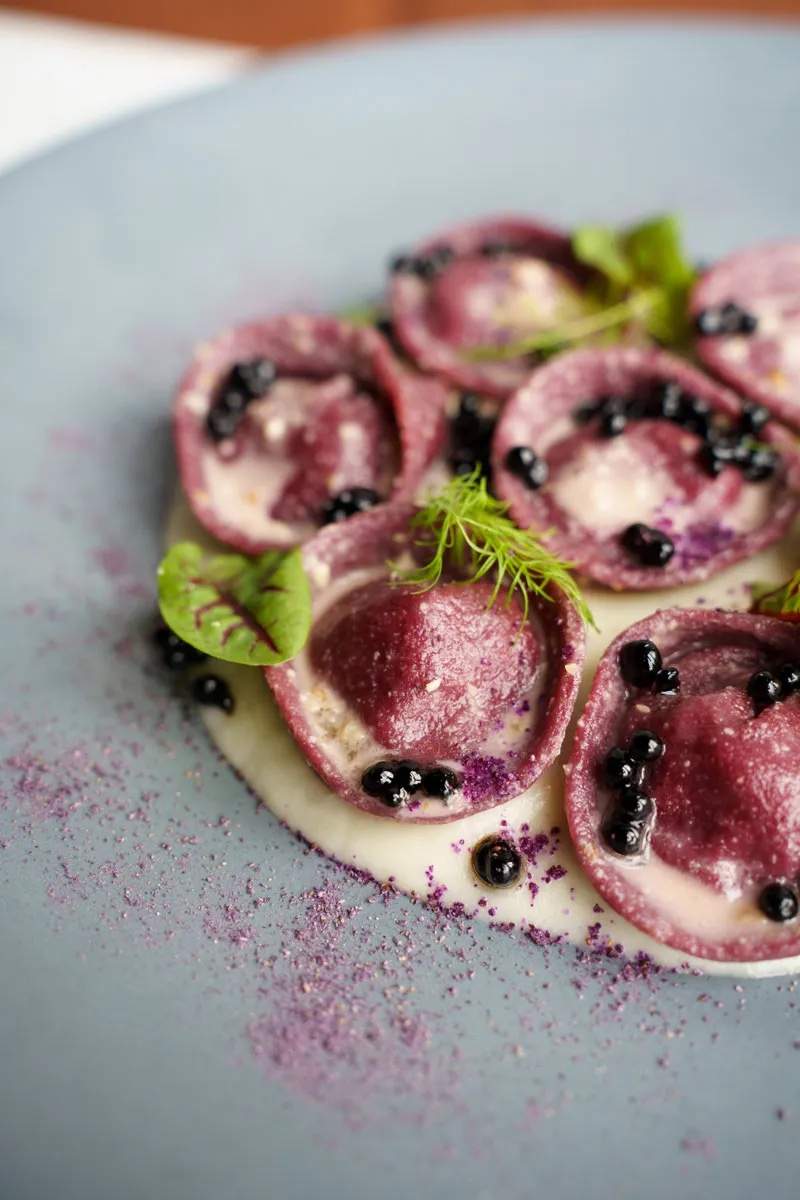 Maroon colored beet pasta with a creamy white sauce at Toronto Italian restaurant Gia.