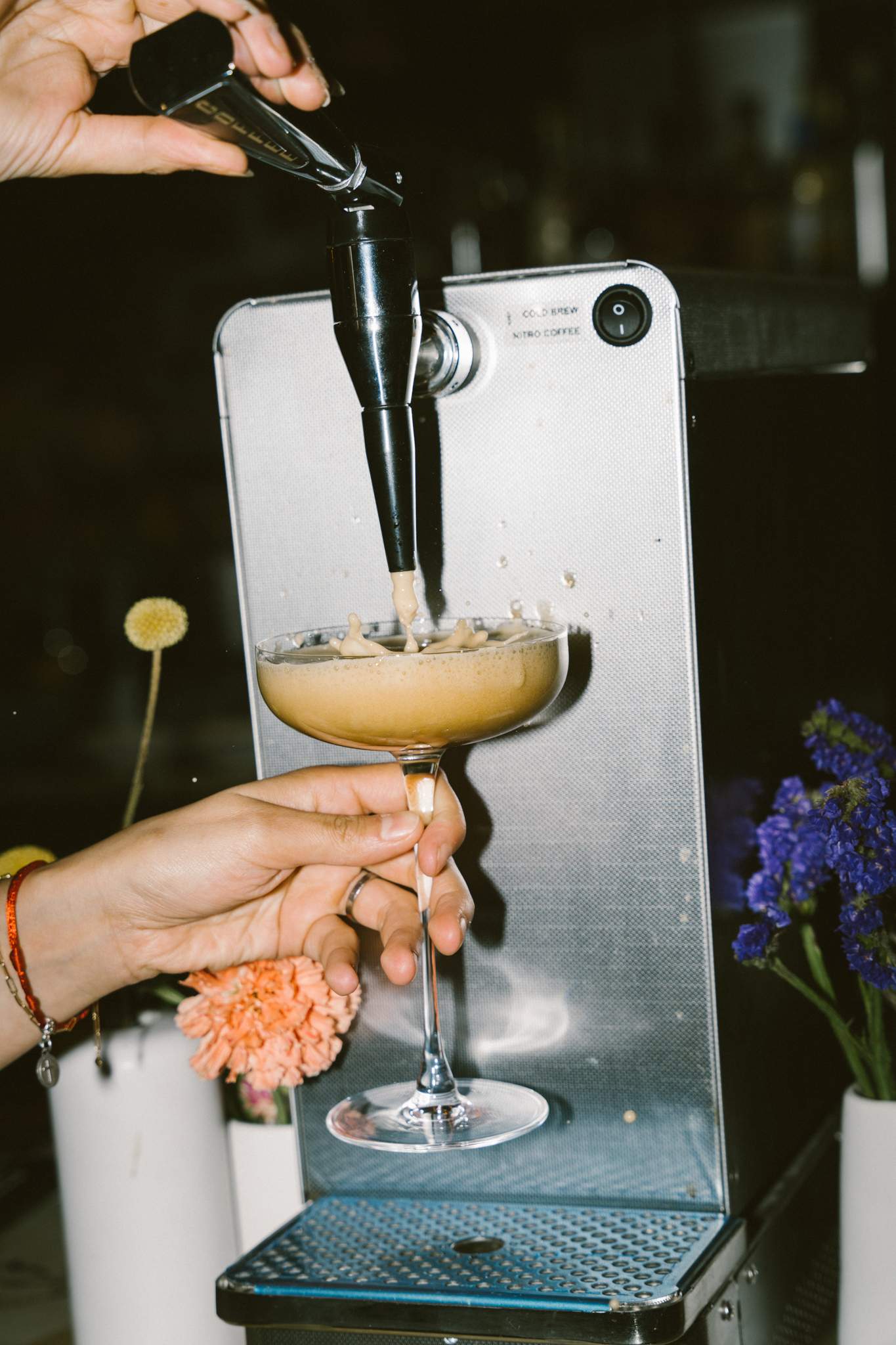 A hand holds a coupe under a frozen cocktail machine dispenser at Sabrosa, one of the best new restaurant in Montreal for 2023.