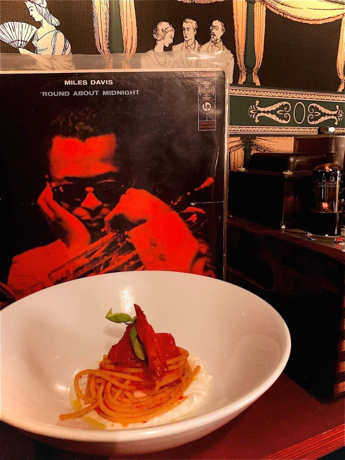 Un plat de spaghetti délicatement enroulé est posé devant la pochette d'un vinyle de Miles Davis au Barcola Bistro à Montréal.