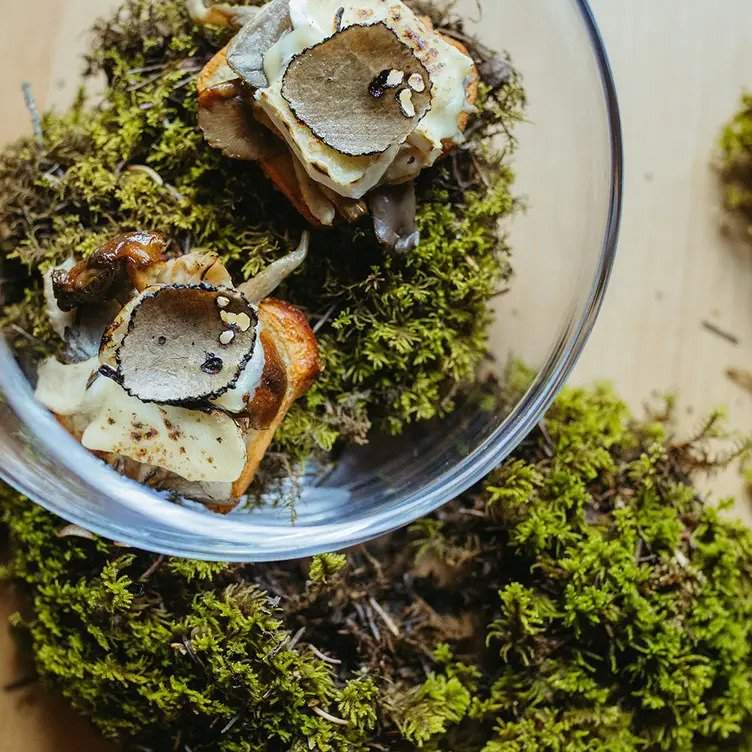 Greens and thinly sliced mushrooms in a glass serving bowl at Calgary restaurant Sauvage.