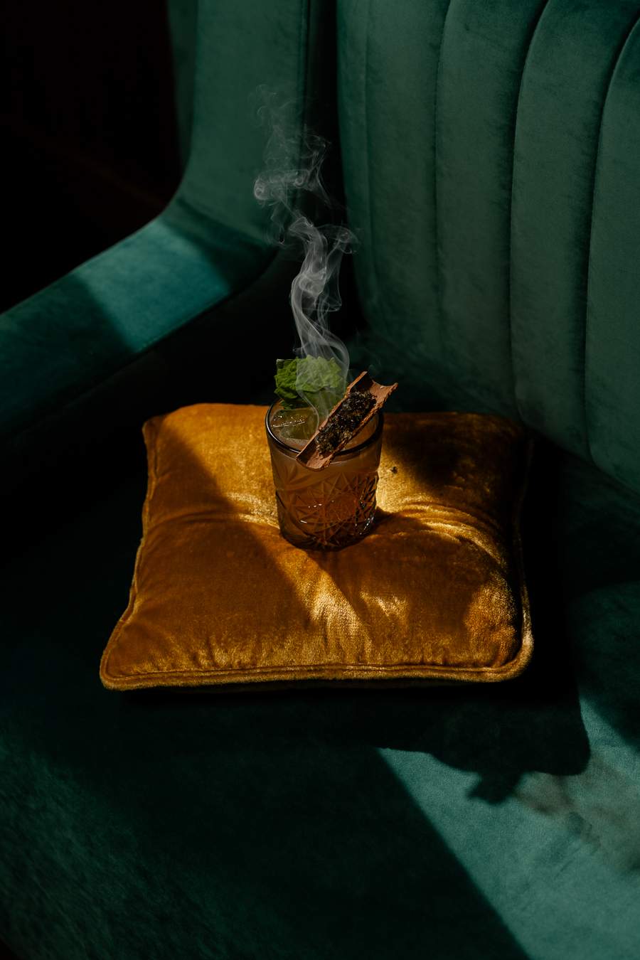 A smoky cocktail rests on a yellow velvet pillow at Kissa in Toronto.