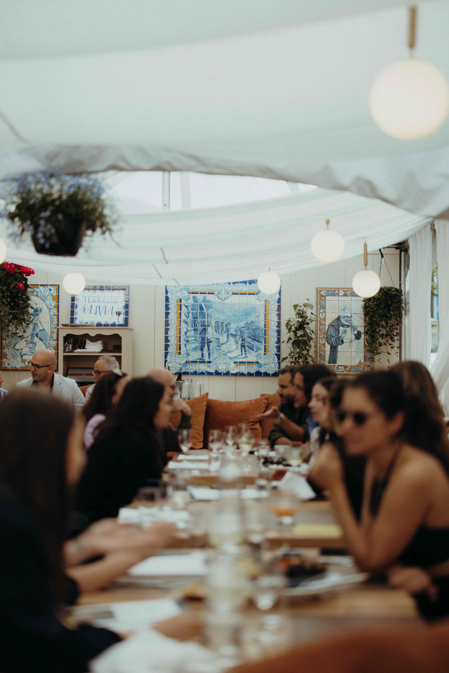 Une longue table avec des convives assis des deux côtés au restaurant montréalais Ferreira Café.