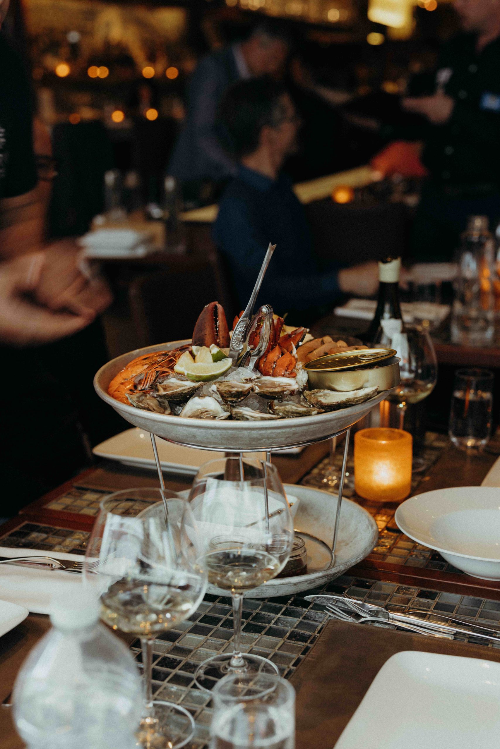 Une assiette à deux niveaux de homard, d'huîtres et d'autres fruits de mer sur une table carrelée du restaurant montréalais Ferreira Café.