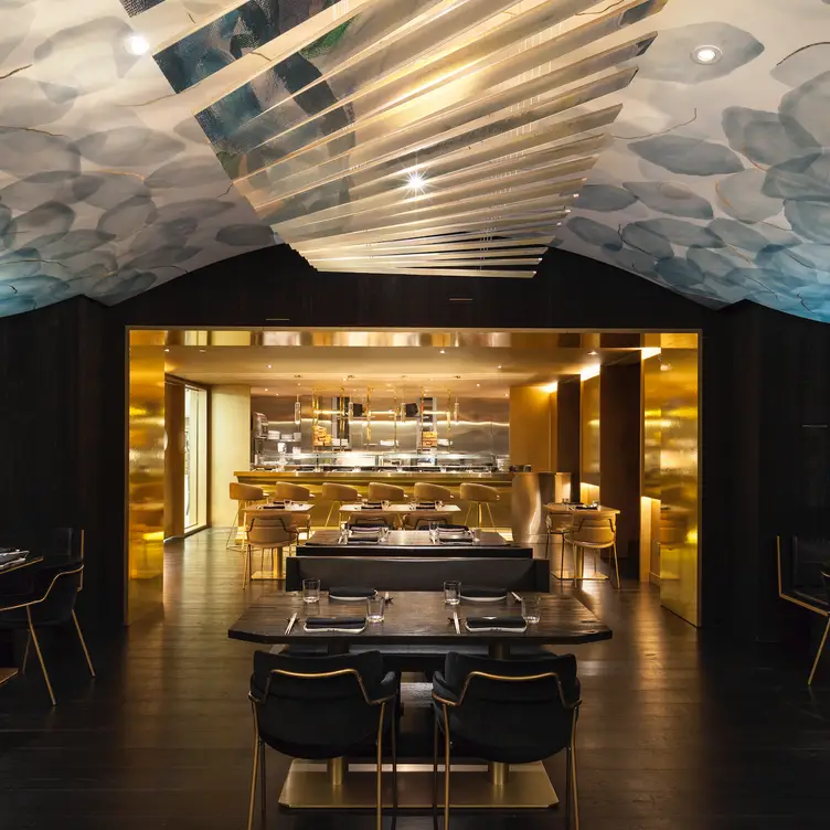 The black and gold dining area under a blue ceiling at Akira Back in Toronto.