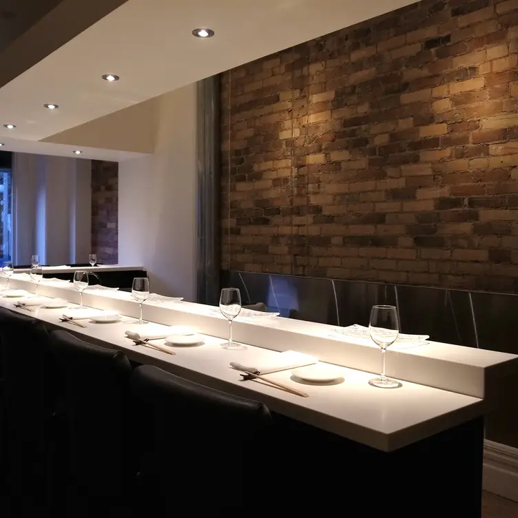 Diners sit together on sleek black and white furnishings at Yasu, one of the best Asian restaurants in Toronto.