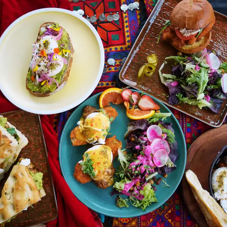 A table at Zarak by Afghan Kitchen, one of the best vegetarian restaurants in Vancouver, set with multiple dishes on a colourful cloth.