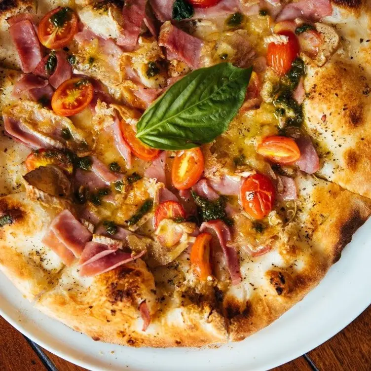 Une pizza avec des tomates cerises, du fromage de brie, du prosciutto cotto, du pesto de basilic de chez Corneli, l’un des meilleurs restaurants de la petite Italie de Montréal.