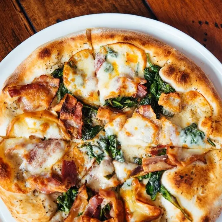 Une pizza avec de la mozzarella, de la roquette, du prosciutto et du parmesan dans une grande assiette de chez Corneli, l’un des meilleurs restaurants de la petite Italie de Montréal.