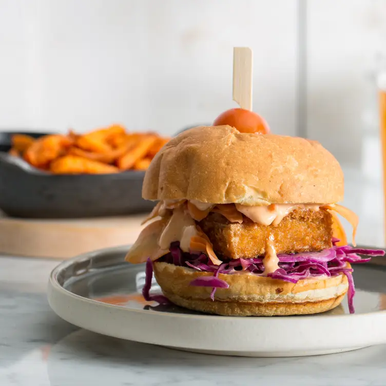 Un burger végétarien dans une assiette devant une assiette de frites de patates douces chez LOV McGill, l’un des meilleurs restaurants végans de Montréal.