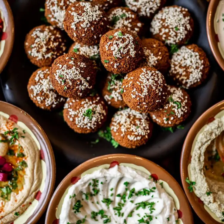 Une grande assiette de falafels avec du sésame entourée par des bols de sauces au yaourt et de hummus de chez Sham Mont-Royal, l’un des meilleurs restaurants végans de Montréal.