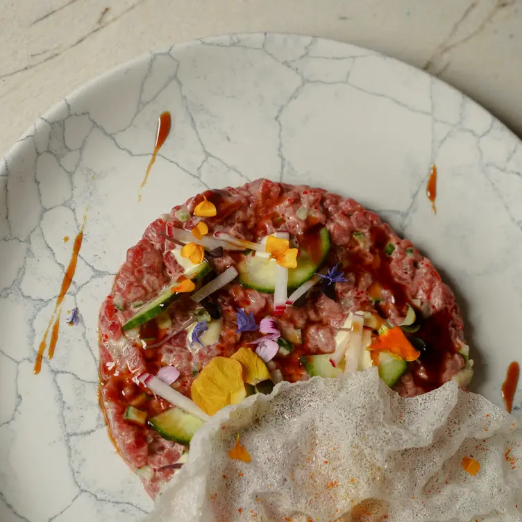 Un tartare de bœuf avec du concombre, des fleurs et une feuille de riz frite de chez Yoko Luna.