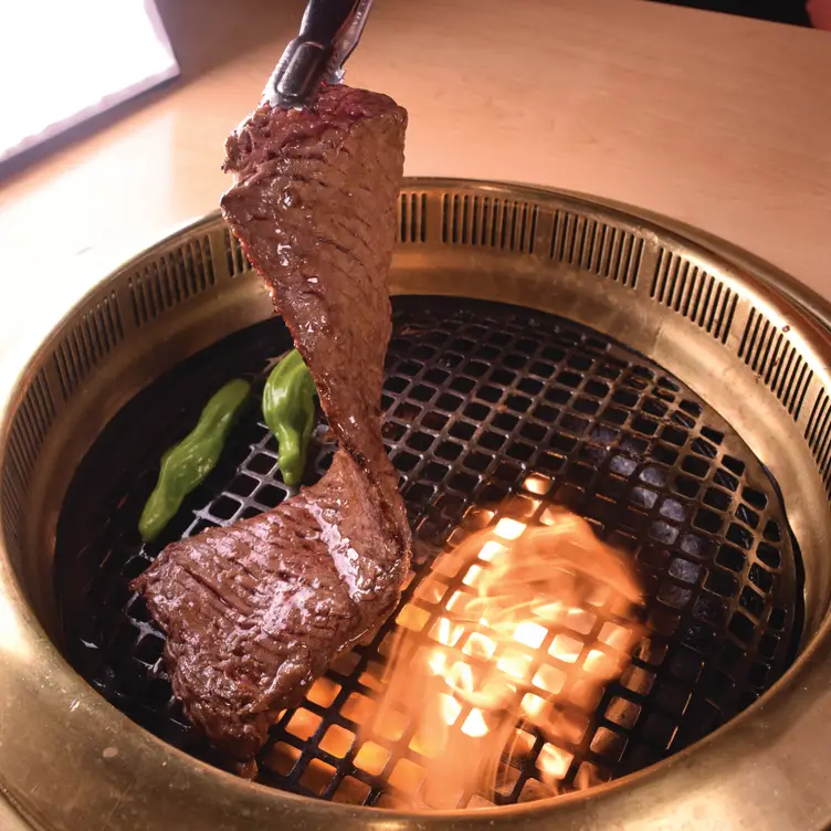 Beef is cooked on a table grill with peppers at Gyu-Kaku, one of the best Japanese restaurants in Toronto.