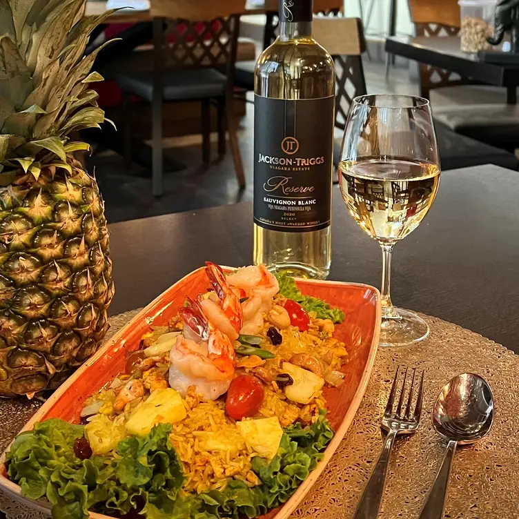 A whole pineapple with shrimp on rice and a glass of white wine at Niagara’s Finest Thai, one of the best Thai restaurants near Toronto.