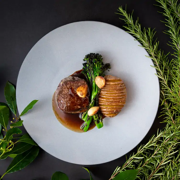 Tender steak with garlic, broccolini, and potatoes, served at one of the best romantic restaurants in Vancouver.