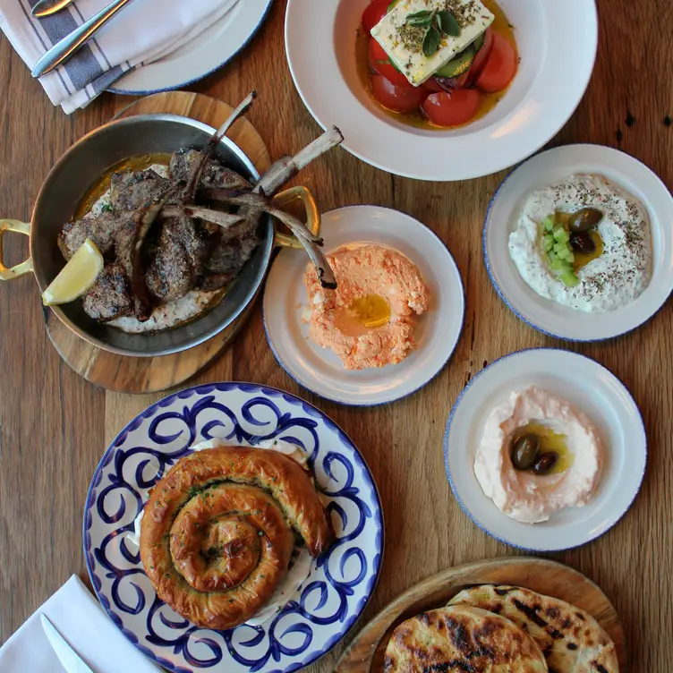 Lamb chops, pita, and housemade dips with spanakopita at Mamakas Taverna, one of the best Greek restaurants Toronto has to offer.