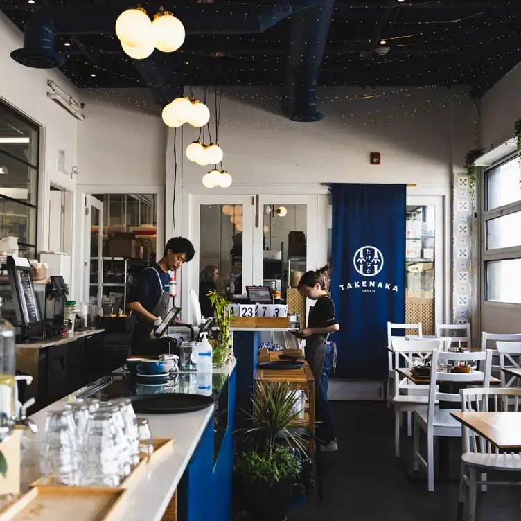 A view of the bright interior of TAKENAKA – Onigiri Cafe, with set tables close to a wall of windows.