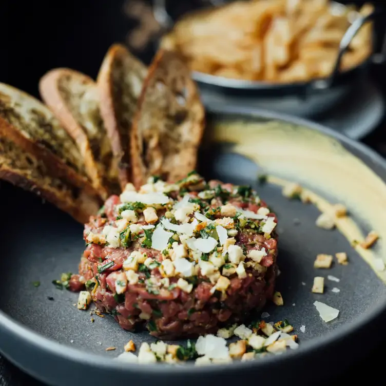 Une assiette de tartare de bœuf avec des morceaux de baguette grillés de chez Modavie, l’un des meilleurs restaurants français de Montréal.