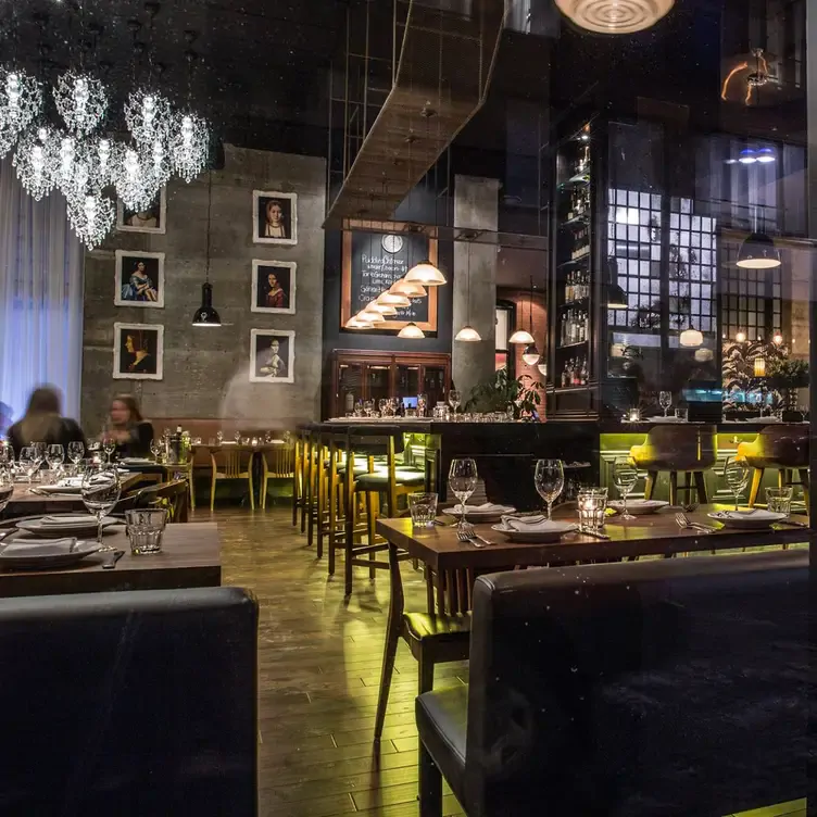 Une grande salle avec des tables, un bar devant un mur avec des peintures de la renaissance de chez Jellyfish, l’un des meilleurs restaurants français à Montréal.