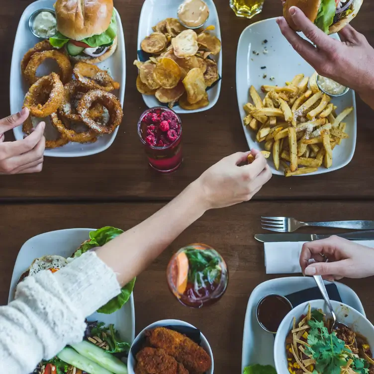 A set table with dishes with a burger, onion rings, fries and drinks at Bin 4 Burger, one of the best family restaurants in Vancouver.