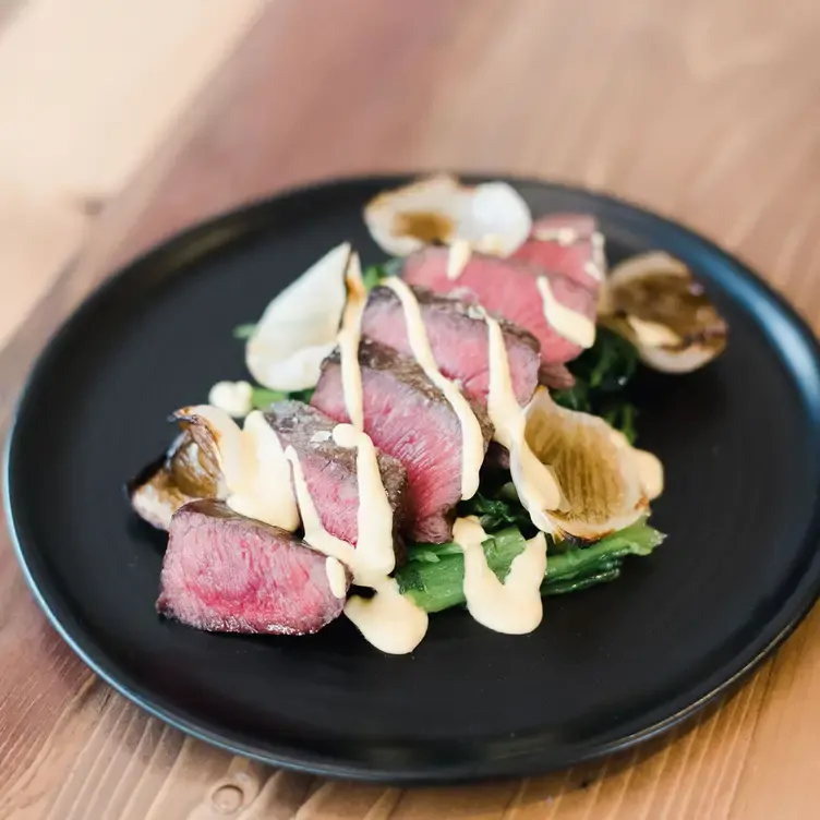 A shareable sliced striploin steak with truffle Dijon sauce at Ten Foot Henry, one of the best date night restaurants Calgary offers.