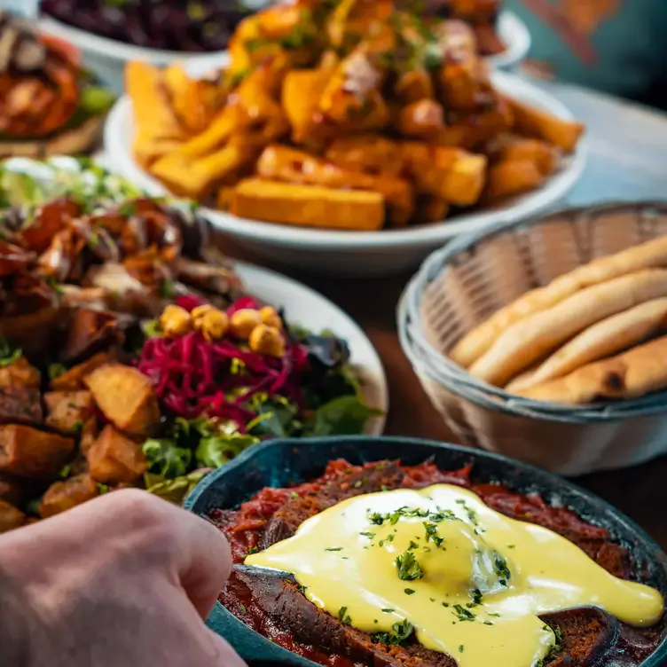 View of various plates, with fries, a basket of pitas and a salad at Chickpea, one of the best family restaurants in Vancouver.