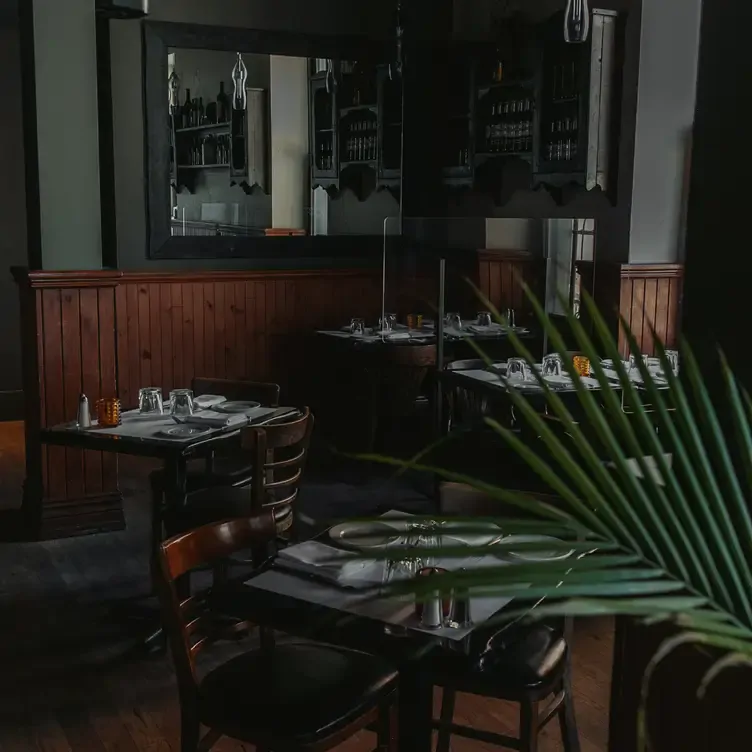 Quatre tables avec des assiettes, des verres, des ustensiles et des chaises dans un décor de café parisien de chez Modavie, l’un des meilleurs restaurants français de Montréal.