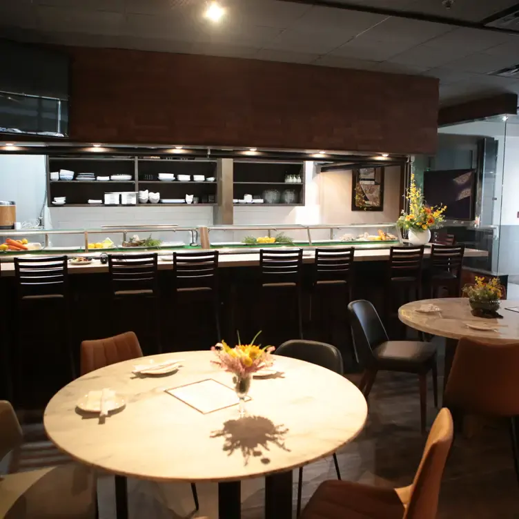 A view of the interior of Guu’s restaurant with round tables and a counter.