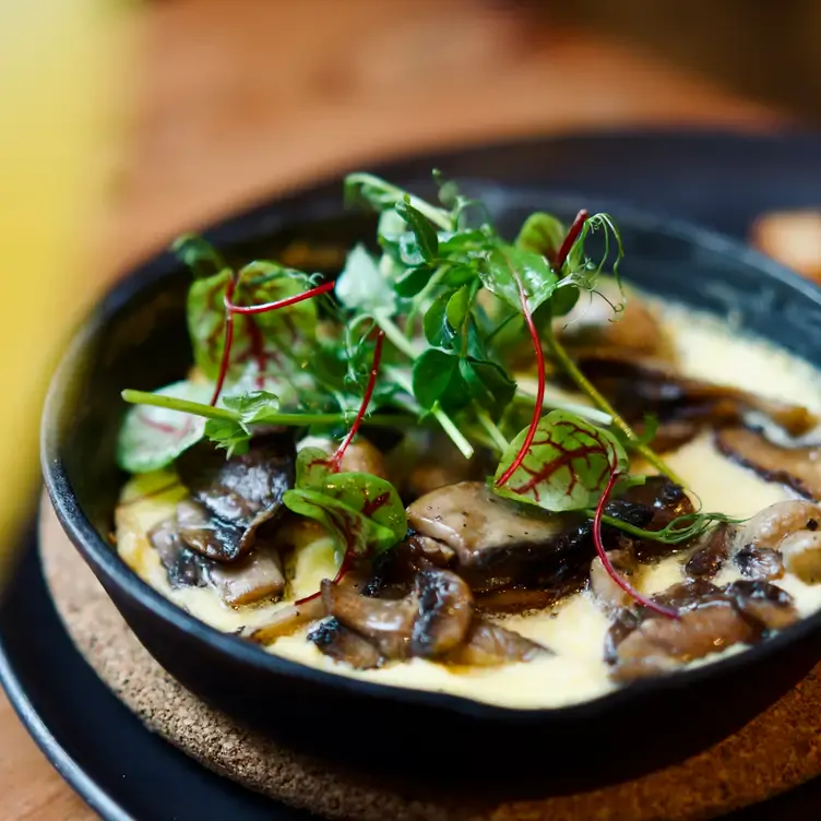 Une assiette avec des champignons sautés avec une sauce à la crème et des herbes aromatiques de chez Le Butterfly, l’un des meilleurs restaurants français de Montréal.