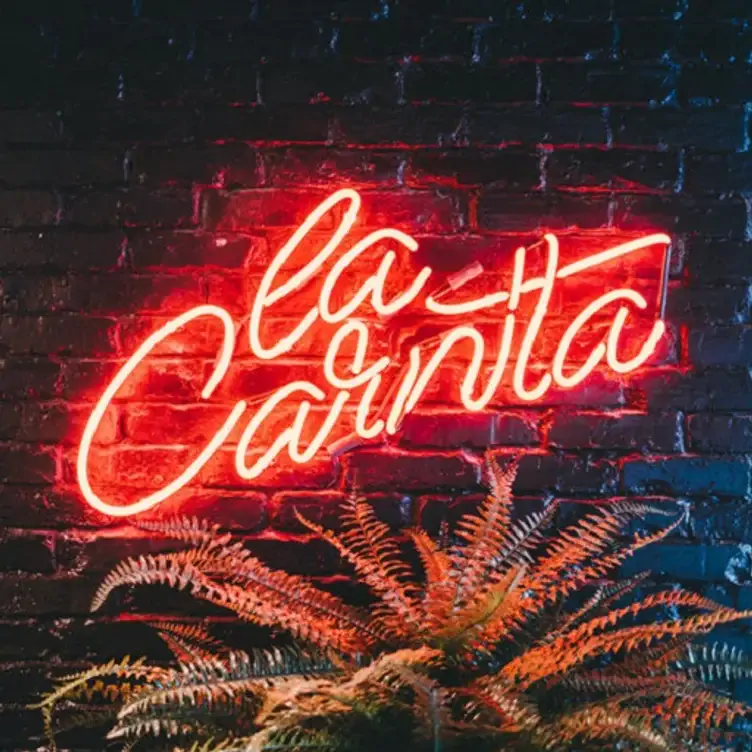 The La Carnita sign lights up on a brick wall at La Carnita, potentially the best Mexican restaurant in Toronto.