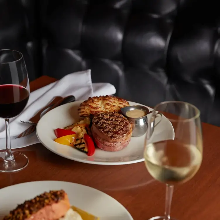 Steak and red wine with roasted vegetables at The Keg Steakhouse + Bar, one of the best family-friendly restaurants in Calgary.