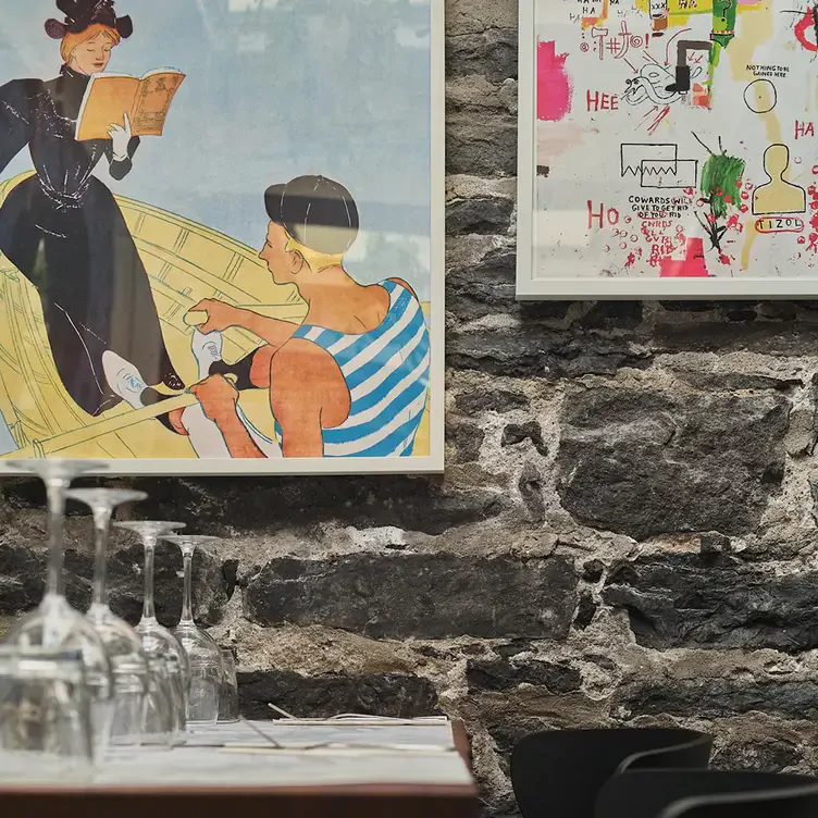 Une affiche vintage derrière une rangée de tables chez Le Polisson, l’un des meilleurs restaurants français à Montréal.