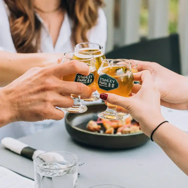 4 people toasting a craft beer at Stanley Park Brewing Restaurant & Brewpub, one of the best family restaurants in Vancouver.