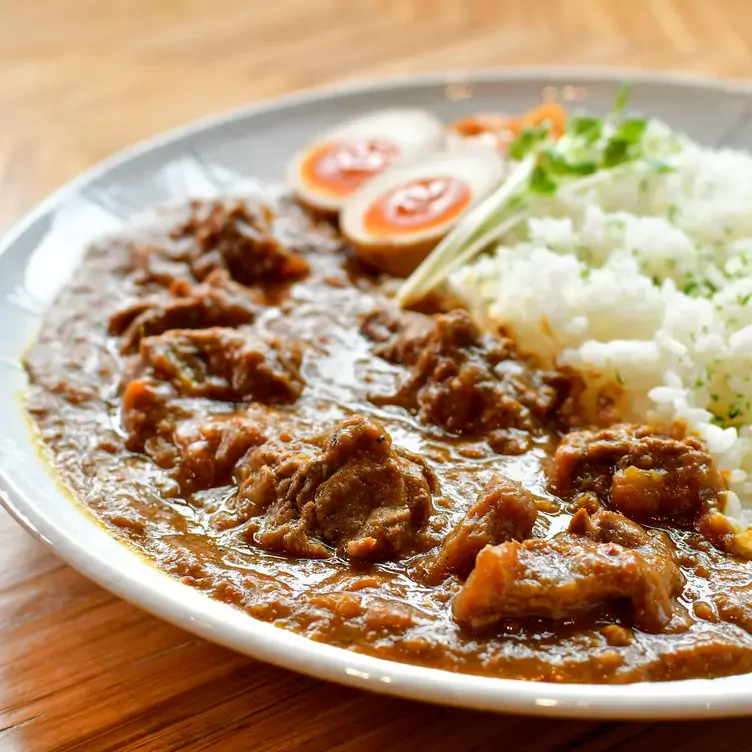 Onigiri Cafe’s serving of Stewed Beef Tendon with a curry sauce is enhanced with garnish.